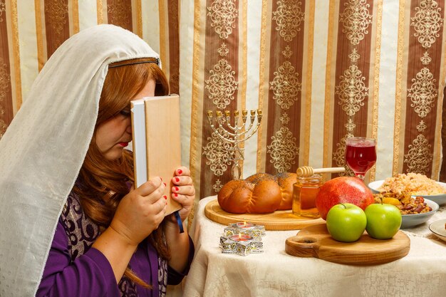 Photo a jewish woman in a headscarf that falls from her hair holds a siddur to her face after the holiday prayer for shabbat and rosh hashanah