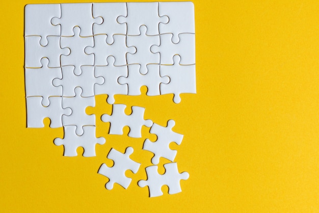 Jigsaw puzzles placed on a yellow background Creative concept with copy space