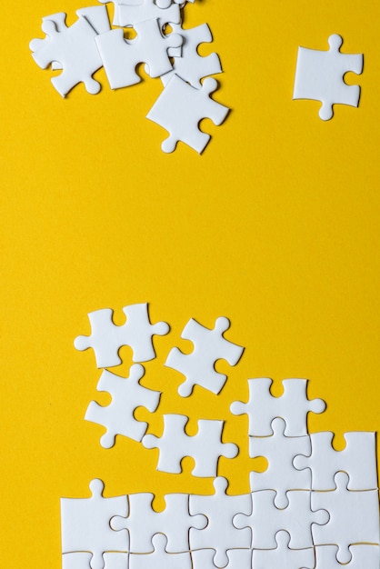 Jigsaw puzzles placed on a yellow background Creative concept with copy space