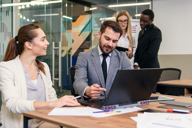 Joined work of two confident business people in formal suit working together with laptop