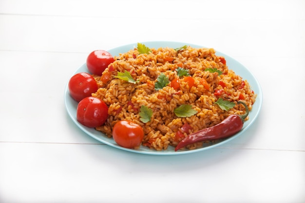 Jollof rice tomatoes and hot peppers on a blue plate on a white background National cuisine of Africa