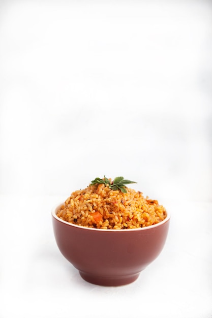 Jollof rice with parsley in a ceramic cup on a white background National cuisine of Africa Copy spaes