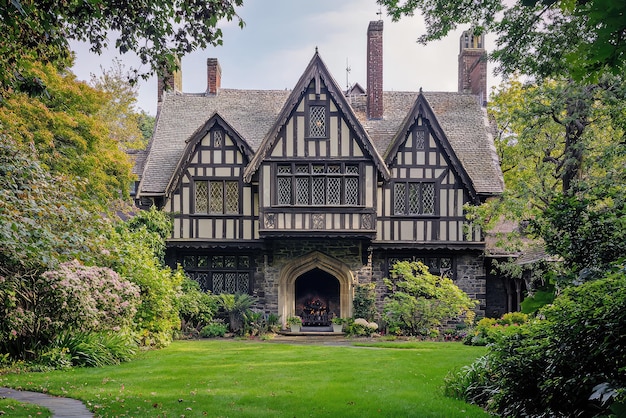 Journey back in time with this magnificent Tudor mansion showcasing steeply pitched roofs intricate halftimbered detailing and lush green surroundings