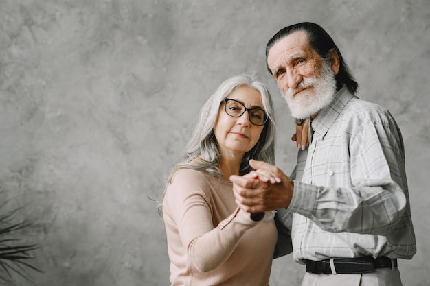 Joyful active old retired romantic couple dancing in living room.