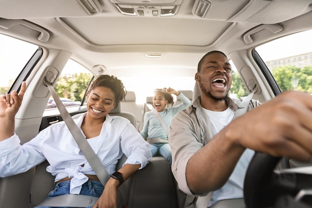 Joyful african american family riding new car singing having fun