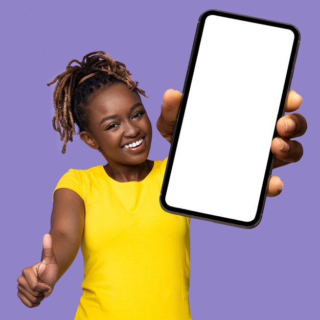 Joyful african american woman showing celll phone and thumb up