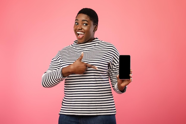 Joyful African Lady Showing Cellphone Blank Screen On Pink Background