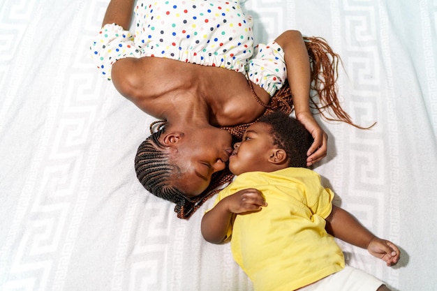 Joyful African mom kisses child in bright room sharing love and happiness