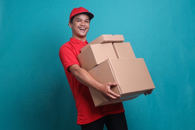 Joyful Asian delivery man holding pile of cardboard boxes