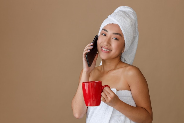 Joyful asian woman talking on cellphone after shower