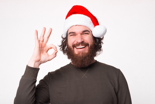 Joyful bearded man smiling and showing OK gesture