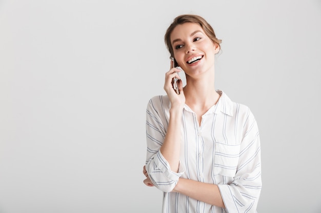 joyful beautiful woman laughing and talking on cellphone isolated over white background