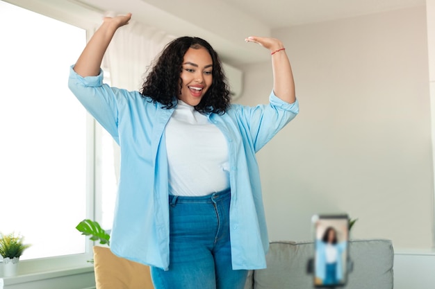 Joyful Black Blogger Lady Dancing Filming Video On Cellphone Indoors