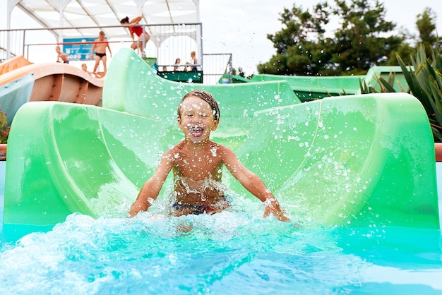 Joyful boy descends from the water slide in the water park childrens attractions in the water park