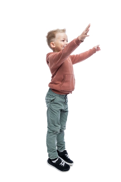 The joyful boy raised his hands up A blond guy in a brown hoodie and gray trousers Positivity and happiness Isolated on white background Vertical