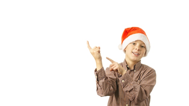 Joyful child in Santa Claus cap points with fingers, isolated on white background. concept of christmas sales, discounts. banner