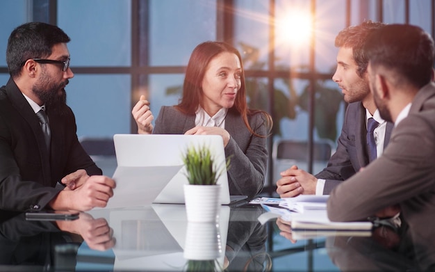 Joyful colleagues discussing project while sitting at table in office