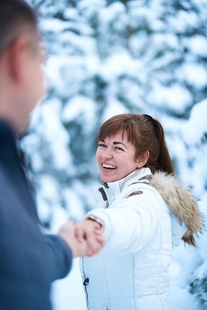 A joyful couple in love walking in winter forest heavy covered with snow