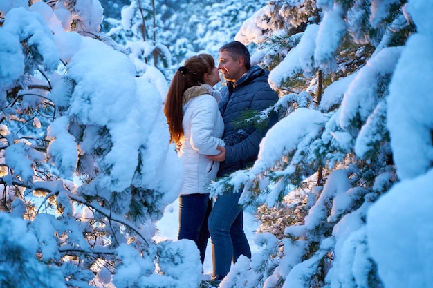 A joyful couple in love walking in winter forest heavy covered with snow