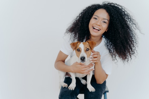 Joyful curly girl petting her dog, rejoicing buying jack russell terrier,