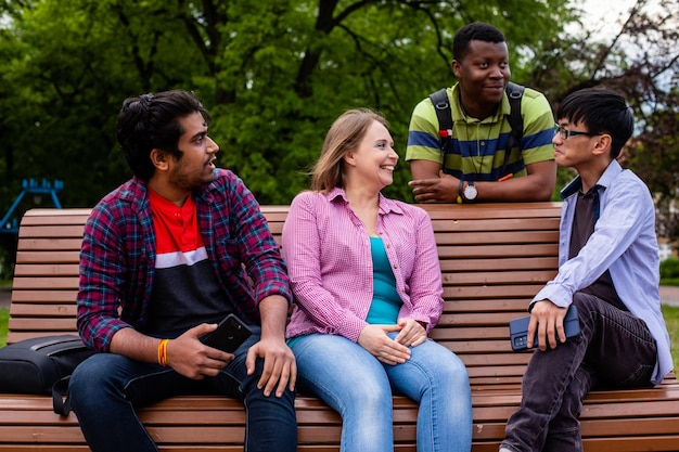 Joyful diverse company of college friends on wooden bench