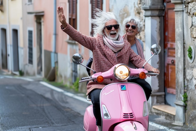 Photo joyful elderly couple on a pink scooter in a historic european town