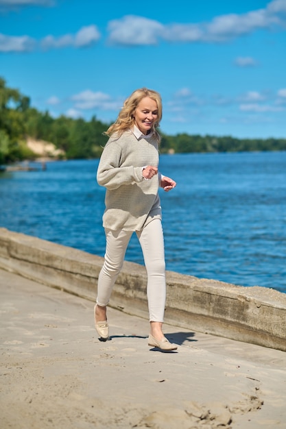 Joyful energetic woman jogging near sea