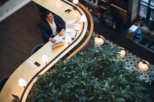 Joyful entrepreneur seated at the table looking away