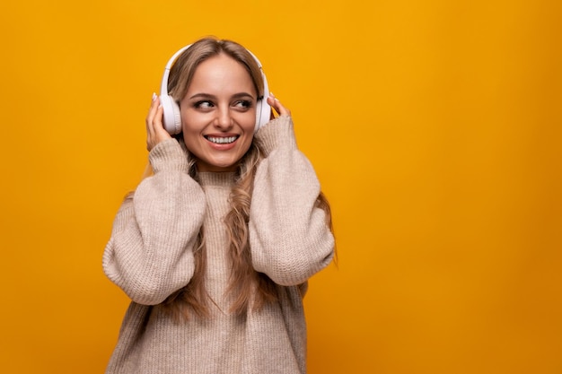 Joyful european young woman enjoying meditation with headphones on yellow background