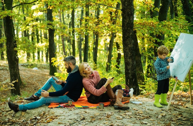 Photo joyful familie picnic handsome years old son drawing family giving joyful moments to mom and dad