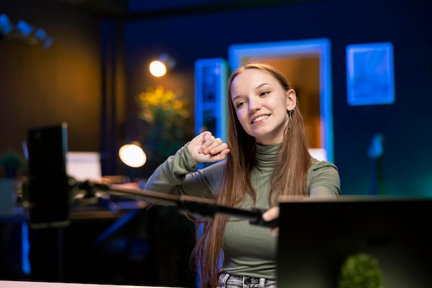 Joyful Gen Z girl records introductory video with smartphone on selfie stick