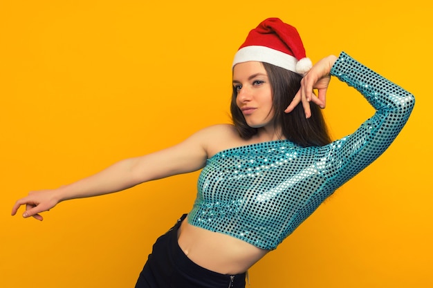 Joyful girl dancing in a Christmas hat on a yellow background - image