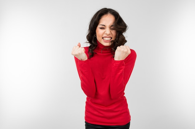 Joyful girl demonstrates victory on a white studio background with copy space.