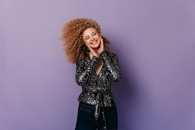 Joyful girl laughs on purple background Woman in stylish elegant glamorous outfit posing with closed eyes