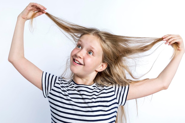 Joyful girl pulls her long red hair Positive and funny mood White background