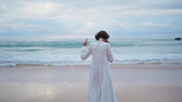 Joyful girl speaking smartphone at ocean shore carefree woman walking beach