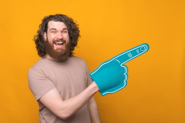 joyful handsome bearded man smiling and pointing with fan glove