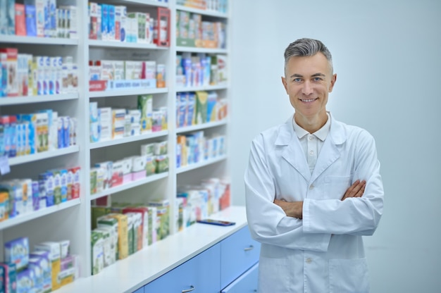 Joyful handsome pharmacist posing for the camera in the workplace