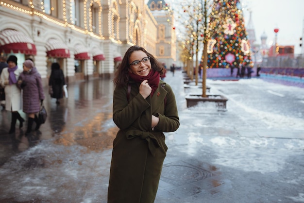 Joyful happy girl enjoying snowing weather on street Fashionable young woman with long brunette hair walking in snowfall having fun smiling Christmas mood new year coming true happiness