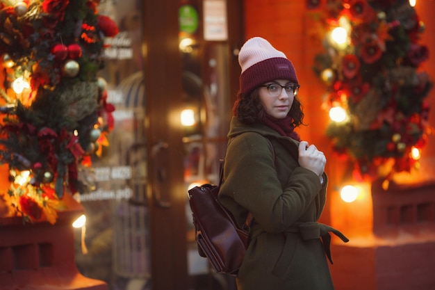 Joyful happy girl enjoying snowing weather on street Smiling and enjoying life Wearing stylish fur coat knitted hat and wide scarf Festive mood Christmas mood true happiness