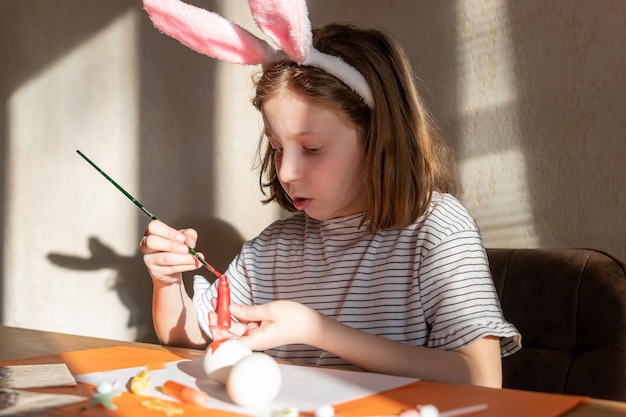 Joyful happy girl having fun and fooling around while decorating easter eggs for spring holidays sit