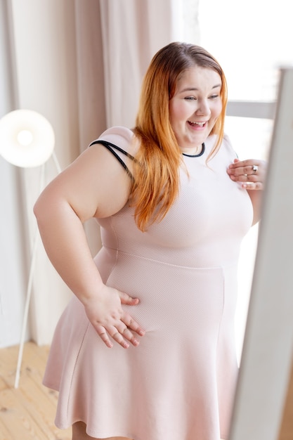  Joyful happy woman looking at her reflection while enjoying her look