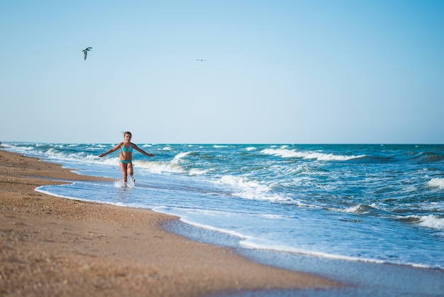 Joyful little girl enjoys a beach day while relaxing at sea on a sunny warm summer day