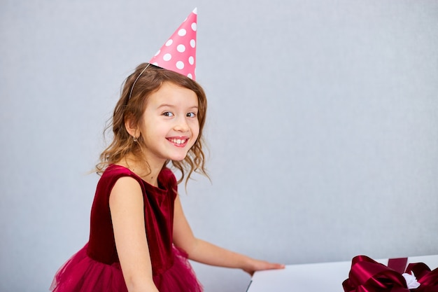 Joyful little girl in pink dress and sneakers with big gift box