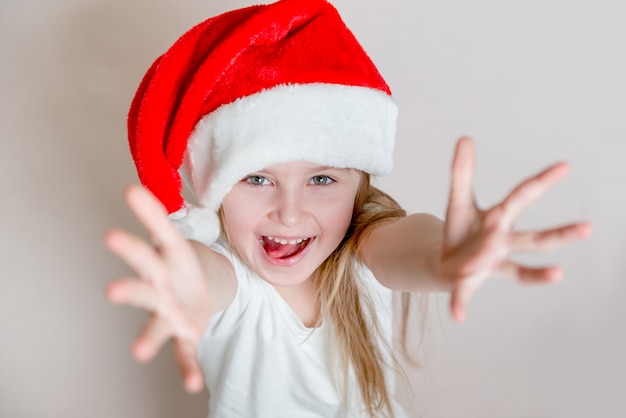 Photo joyful little girl in santa's hat smiles and