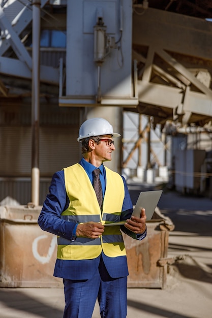 Joyful male engineer using laptop outdoors at factory