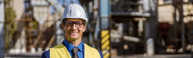 Joyful male engineer using notebook outdoors at factory