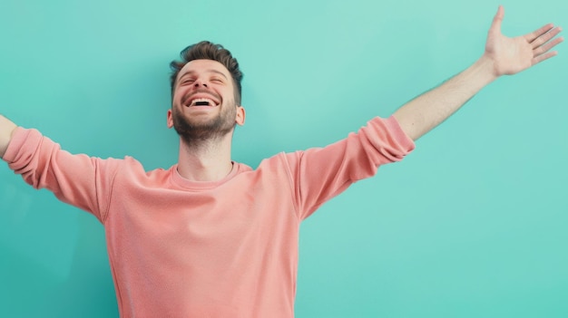 Photo a joyful man in a pink sweater arms spread wide standing against a fresh turquoise background radiating happiness and freedom