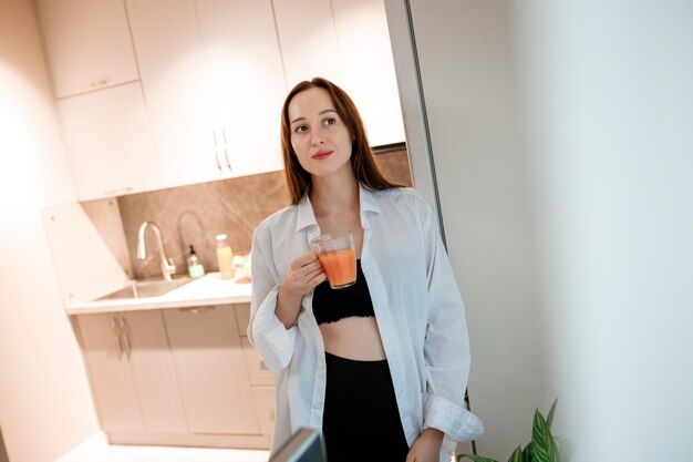 Joyful smiling woman drinking juice at home kitchen Healthy lifestyle concept