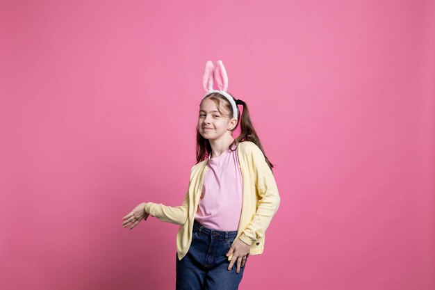 Joyful toddler with pigtails and bunny ears dancing on camera